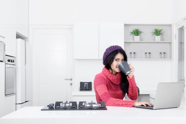 Young woman with laptop in the kitchen