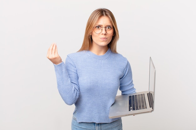 Foto giovane donna con un laptop che fa un gesto capice o denaro, dicendoti di pagare