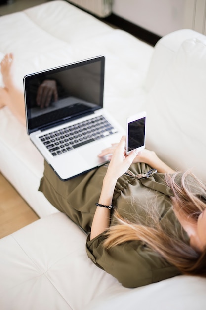 ラップトップと携帯電話を持つ若い女性