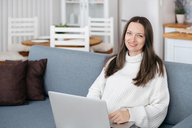Young woman with laptop sitting on the couch