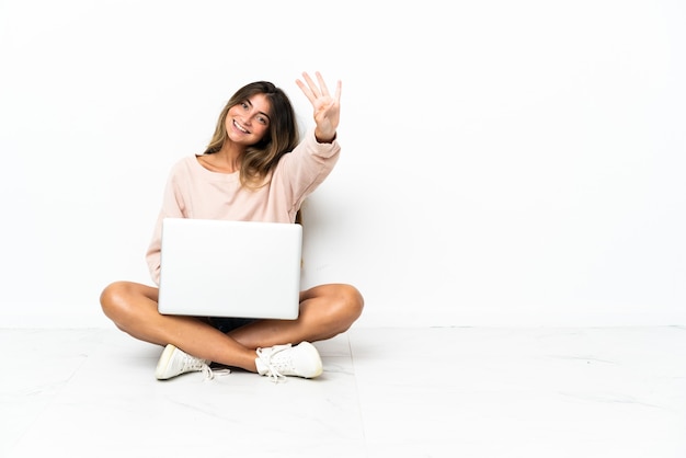 흰색에 고립 된 바닥에 앉아 노트북을 가진 젊은 여자와 손가락으로 4 세