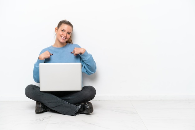 Молодая женщина с ноутбуком сидит на полу гордая и самодовольная