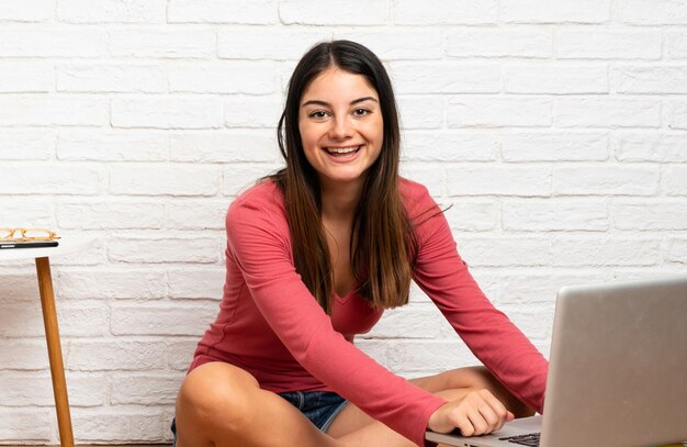 Young woman with a laptop sitting on the floor