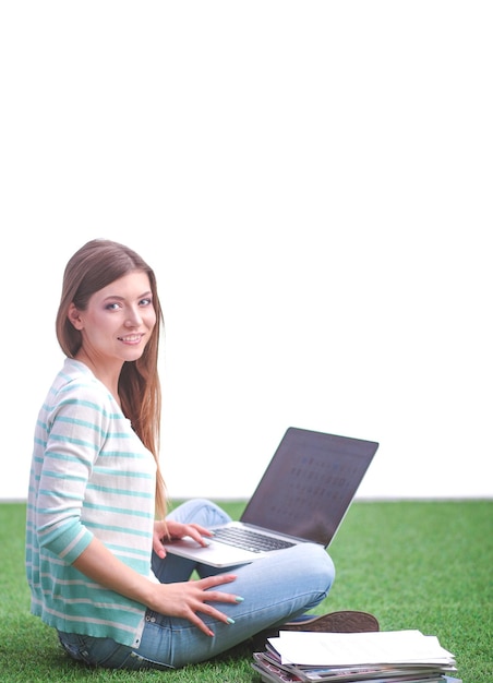 Young woman with laptop sitting on green grass Portreit young woman