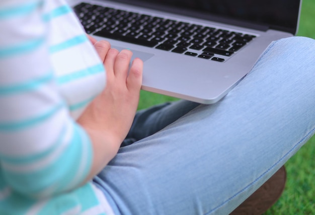 Young woman with laptop sitting on green grass Portreit young woman