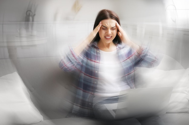 Foto giovane donna con il computer portatile che soffre di emicrania a casa