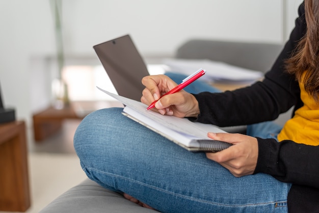 Young woman with laptop telecommuting on the sofa at her home