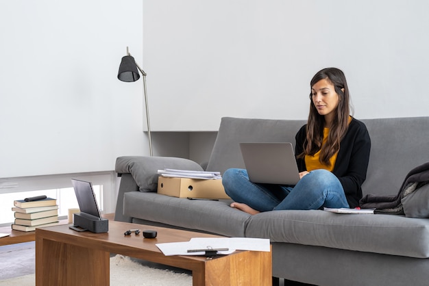 Photo young woman with laptop telecommuting on the sofa at her home