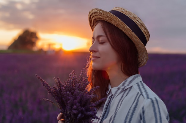 Young woman with lavender bouquet on sunset background