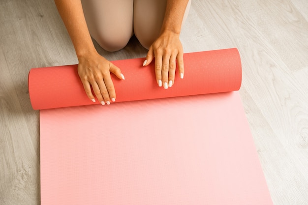 Young woman with long hair fitness instructor in beige sportswear preparing for stretching and