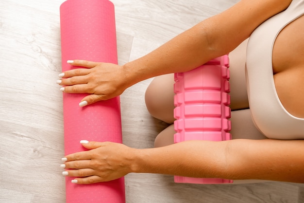 Young woman with long hair fitness instructor in beige sportswear preparing for stretching and