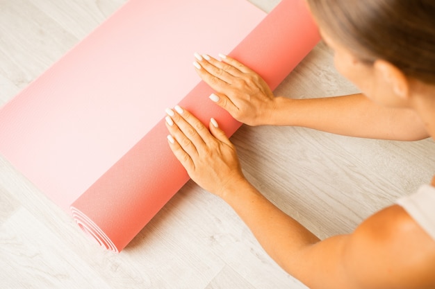 Young woman with long hair fitness instructor in beige sportswear preparing for stretching and