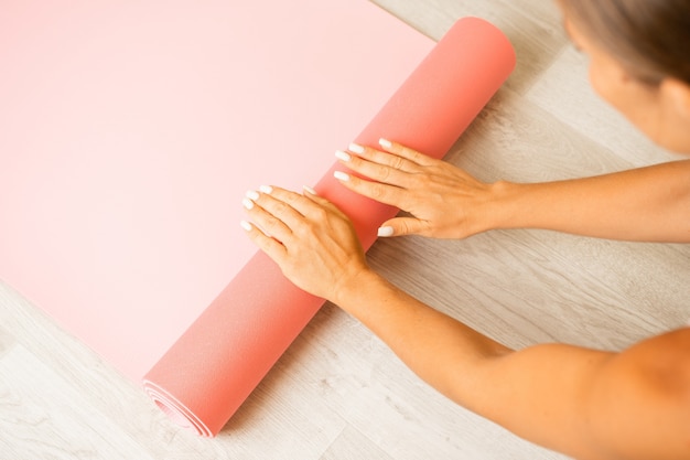 Young woman with long hair fitness instructor in beige sportswear preparing for stretching and