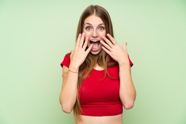 Young woman with long hair over isolated green wall with surprise facial expression