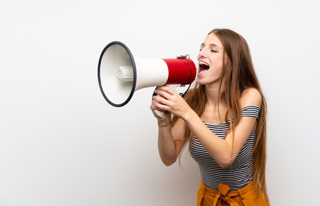 Young woman with long hair over isolated white wall shouting through a megaphone