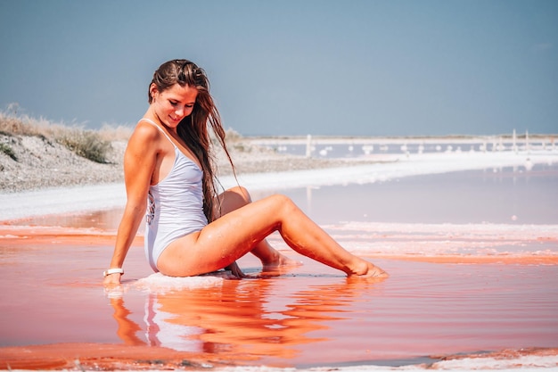 Foto giovane donna con i capelli lunghi in lago salato rosa con cristalli di sale lago rosa estremamente salato