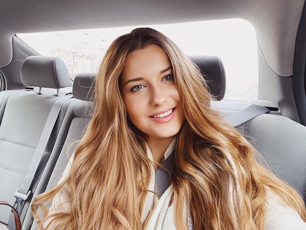 Young woman with long hair wavy hairstyle in the car or taxi cab as passenger exploring the city transport and travel