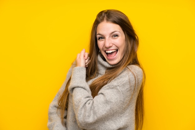 Young woman with long hair over yellow celebrating a victory