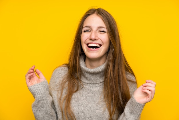 Young woman with long hair over yellow laughing