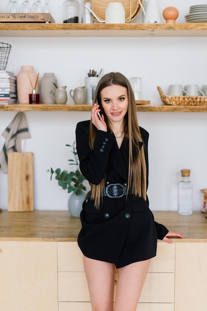 Young woman with long legs and long hair posing on the sofa in a cozy apartment in the morning