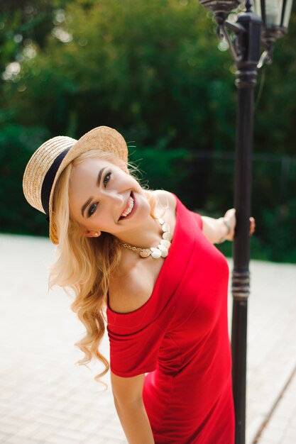 Young woman with long shiny hair gladly posing while walk outside in good mood