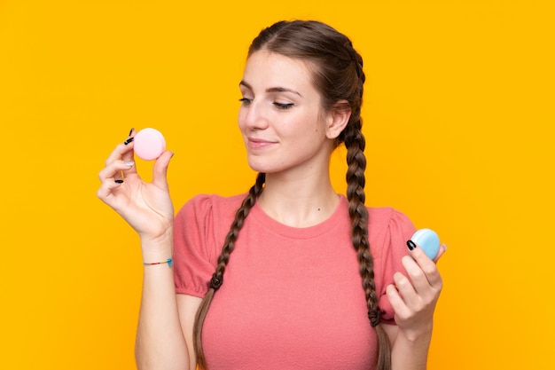 Young woman with macaroons over isolated wall