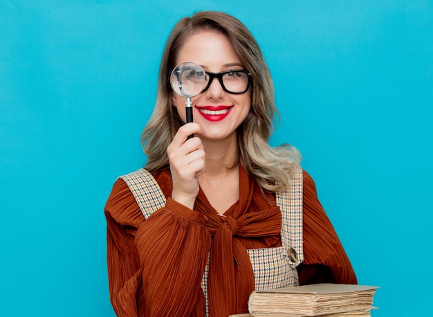 Photo young woman with magnifier and books on blue