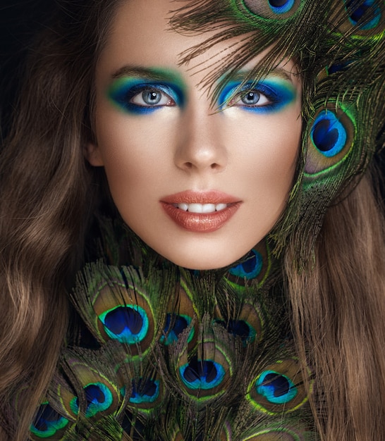 Photo young woman with makeup and colorful peacock feathers