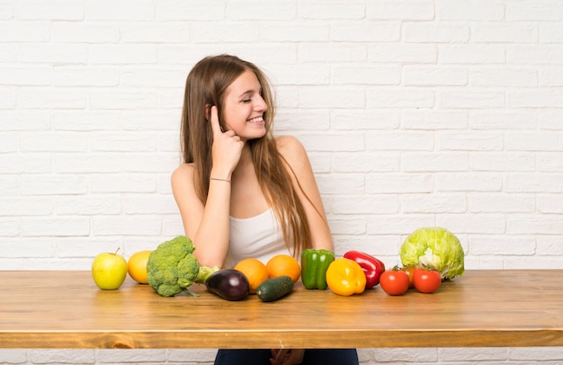 笑っている多くの野菜を持つ若い女性