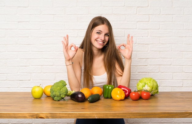 Young woman with many vegetables showing an ok sign with fingers