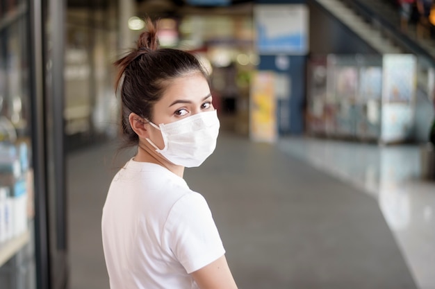 屋外に立っているマスクを持つ若い女