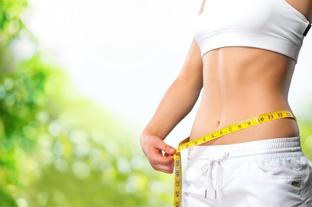 Young woman with measuring tape on her belly