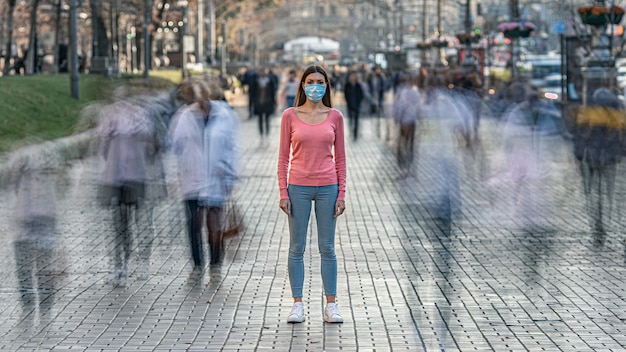 Photo the young woman with medical mask on her face stands on the crowded street