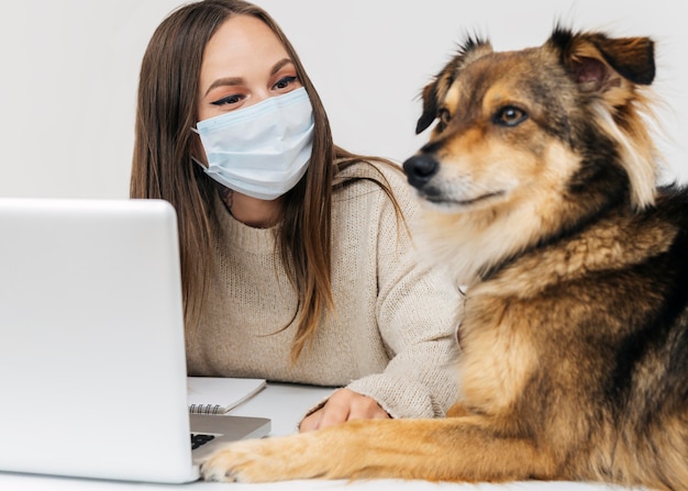 Foto giovane donna con mascherina medica che gioca con il suo cane