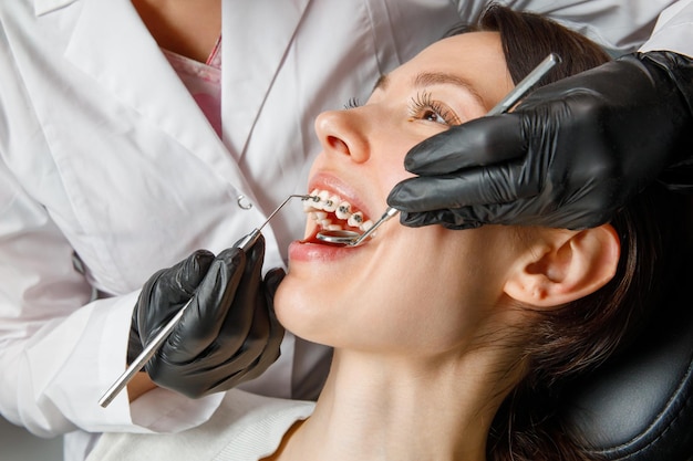 A young woman with metal braces is being examined by an orthodontist correction of the bite of teeth