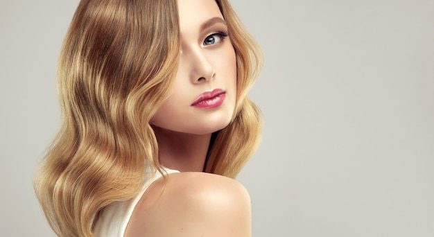 Young woman with middle length wavy hair in a deep blonde color wearing in a delicate evening makeup