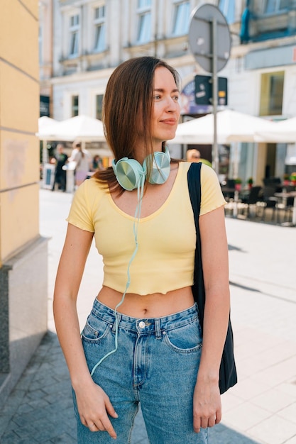 Young woman with mint headphones and black cap outside on the street