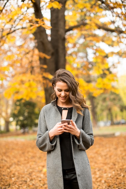 Young woman with mobile phone in autumn park