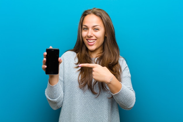 Молодая женщина с мобильным телефоном на синем