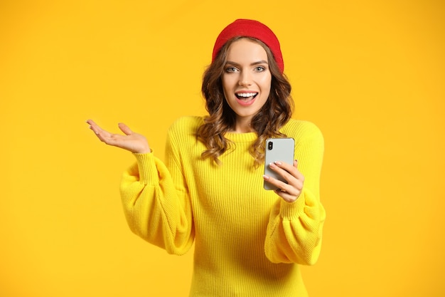 Young woman with mobile phone on color