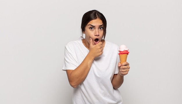 Young woman with mouth and eyes wide open and hand on chin, feeling unpleasantly shocked