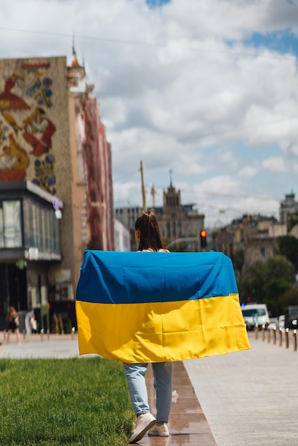 Young woman with national flag of Ukraine on the street