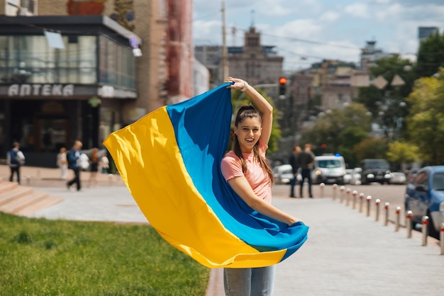 Young woman with national flag of Ukraine on the street