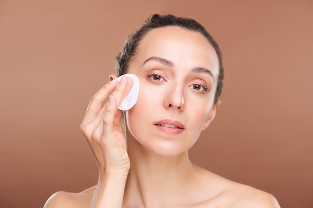 Young woman with natural beauty of her skin applying hydrating toner or micellar water on her face during morning beauty care procedure