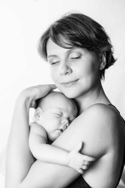 Young woman with a newborn baby girl on her hands with smile on her face