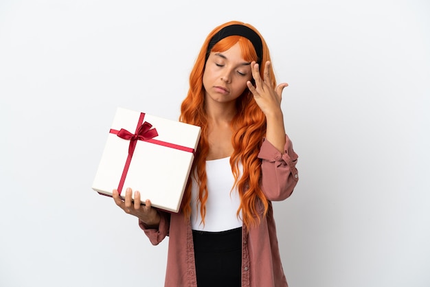 Молодая женщина с оранжевыми волосами держит подарок на белом фоне с головной болью