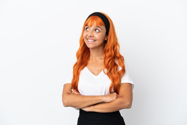 Young woman with orange hair isolated on white background looking up while smiling