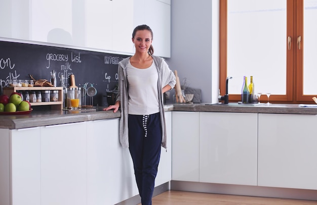 Young woman with orange juice and tablet in kitchen