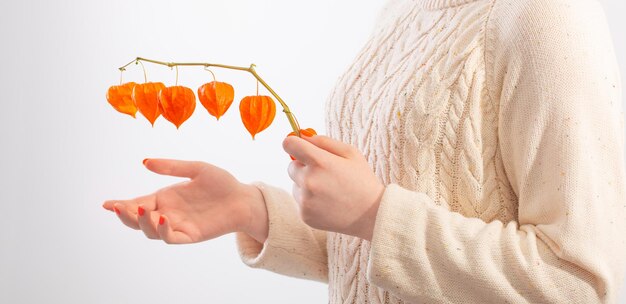 Young woman with orange manicure with physalis on white background