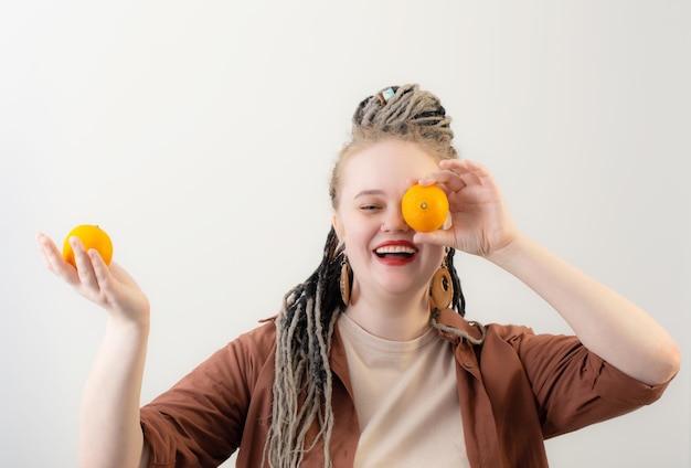 Young woman with orange on white background